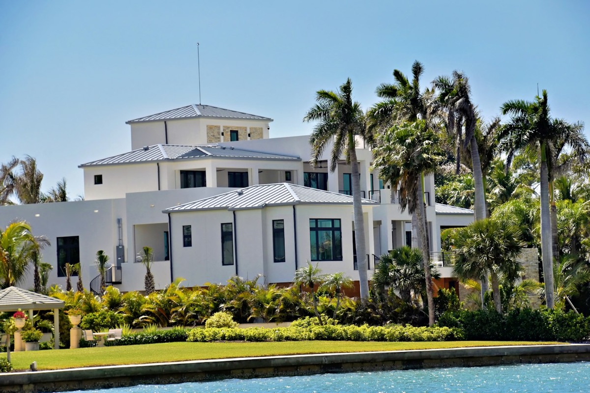 Bright white modern estate with palm trees and a green lawn